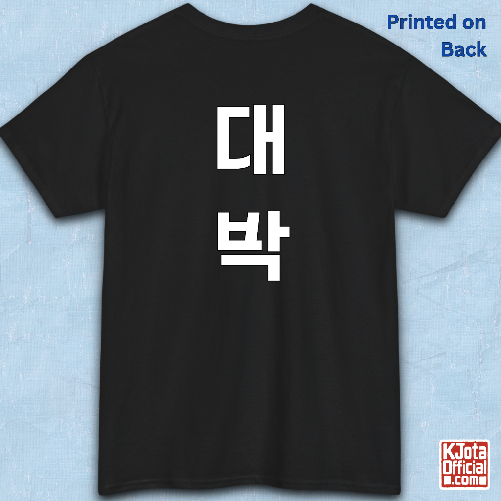 black t-shirt backside flatlay with “대박” Daebak Korean slang Hangeul text printed in white by K-Jota