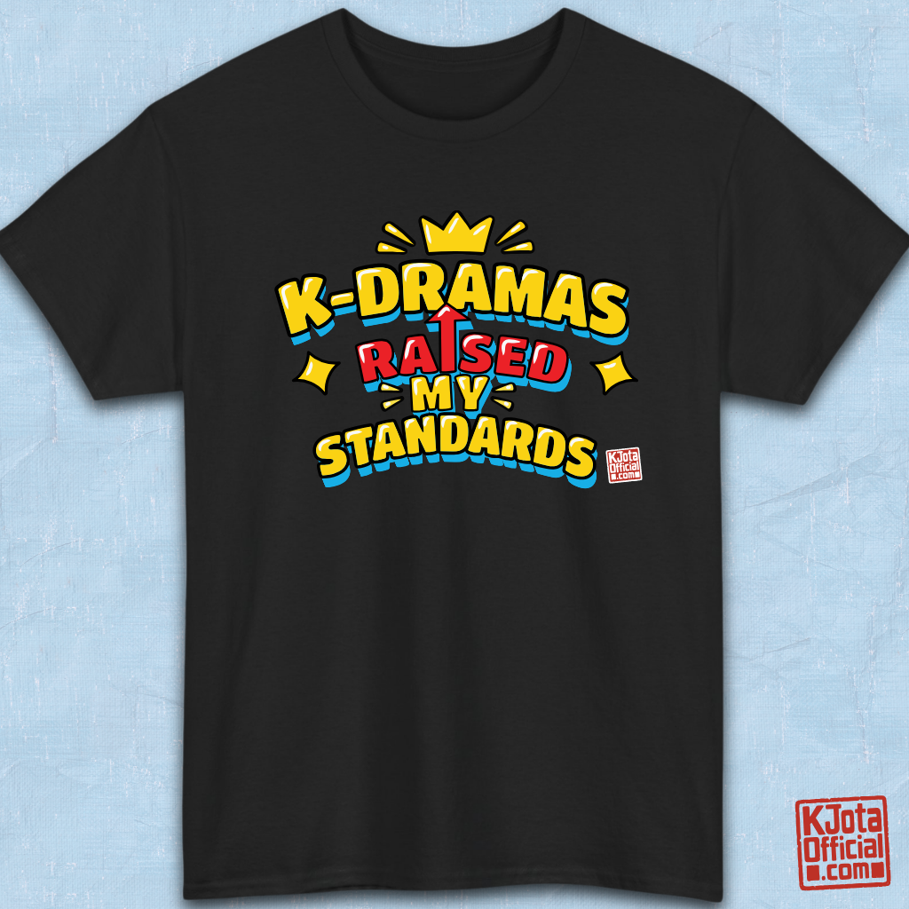'K-DRAMAS RAISED MY STANDARDS' yellow, red, and blue lettering with an uparrow in place of letter “I” printed on a black t-shirt flatlay. Realistic expectations K-fan graphic t-shirt by K-Jota