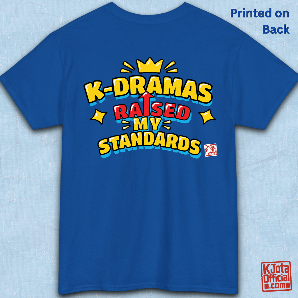 'K-DRAMAS RAISED MY STANDARDS' yellow, red, and blue lettering with an uparrow in place of letter “I” printed on a blue t-shirt baackside flatlay. Realistic expectations K-fan graphic t-shirt by K-Jota