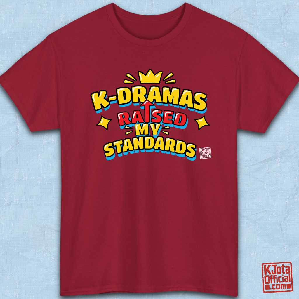 'K-DRAMAS RAISED MY STANDARDS' yellow, red, and blue lettering with an uparrow in place of letter “I” printed on a red t-shirt flatlay. Realistic expectations K-fan graphic t-shirt by K-Jota