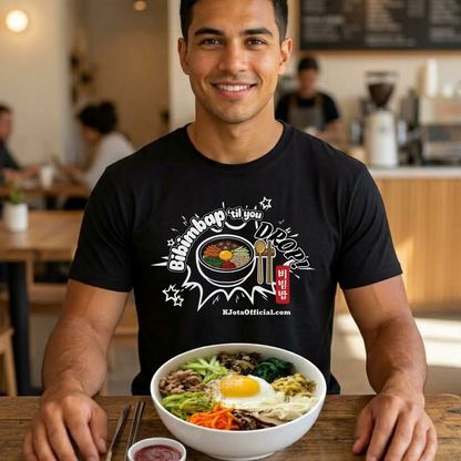 A man wearing a black t-shirt by K-Jota showing Korean food mixed rice bowl and sitting at a table with a bowl of bibimbap. The graphic features a hand-illustrated bowl of bibimbap with a spoon and chopsticks, and texts “Bibimbap ‘til You Drop 비빔밥” and “KJotaOfficial.com”.