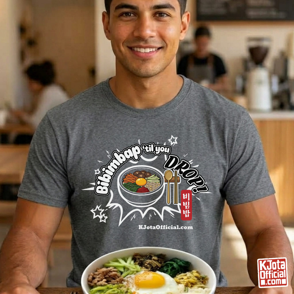A man wearing a gray t-shirt by K-Jota showing Korean food mixed rice bowl and sitting at a table with a bowl of bibimbap. The graphic features a hand-illustrated bowl of bibimbap with a spoon and chopsticks, and texts “Bibimbap ‘til You Drop 비빔밥” and “KJotaOfficial.com”.