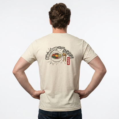 A man viewed from behind wearing a black Korean food fan t-shirt by Kjota with a graphic on the back. The graphic features a bowl of bibimbap with a spoon and chopsticks, and text “Bibimbap ‘til You Drop 비빔밥”