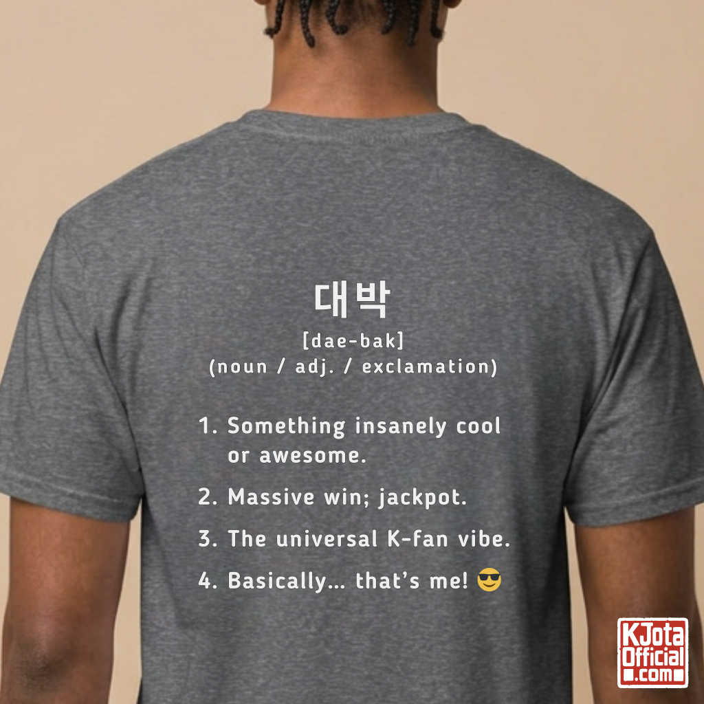 man wearing a gray short-sleeve T-shirt shown from the back with white printed Korean text and a dictionary-style definition of Daebak 대박 Korean slang. K-fandom merch by K-Jota