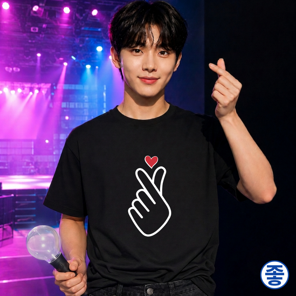 man wearing finger heart Korean saranghaeyo K-pop Hallyu fan t-shirt black by Kjota and making finger heart gesture in one hand and holding a light stick in the other at a concert venue