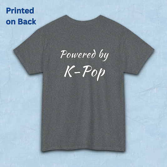 A gray short-sleeve t-shirt flatlay with 'Powered by K-Pop' printed in white script on the back, displayed against a light blue textured background by Kjota