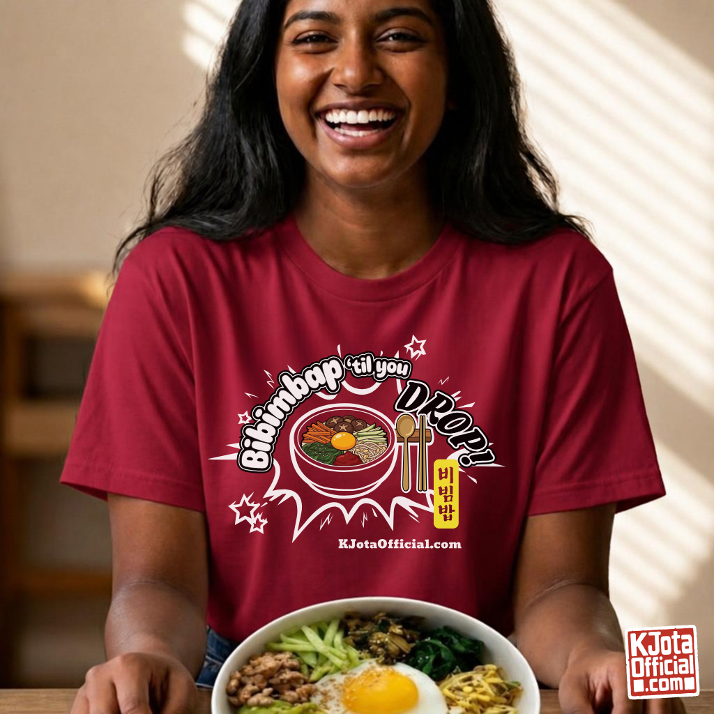 A woman wearing a red t-shirt by K-Jota showing Korean food mixed rice bowl and sitting at a table with a bowl of bibimbap. The graphic features a hand-illustrated bowl of bibimbap with a spoon and chopsticks, and texts “Bibimbap ‘til You Drop 비빔밥” and “KJotaOfficial.com”.