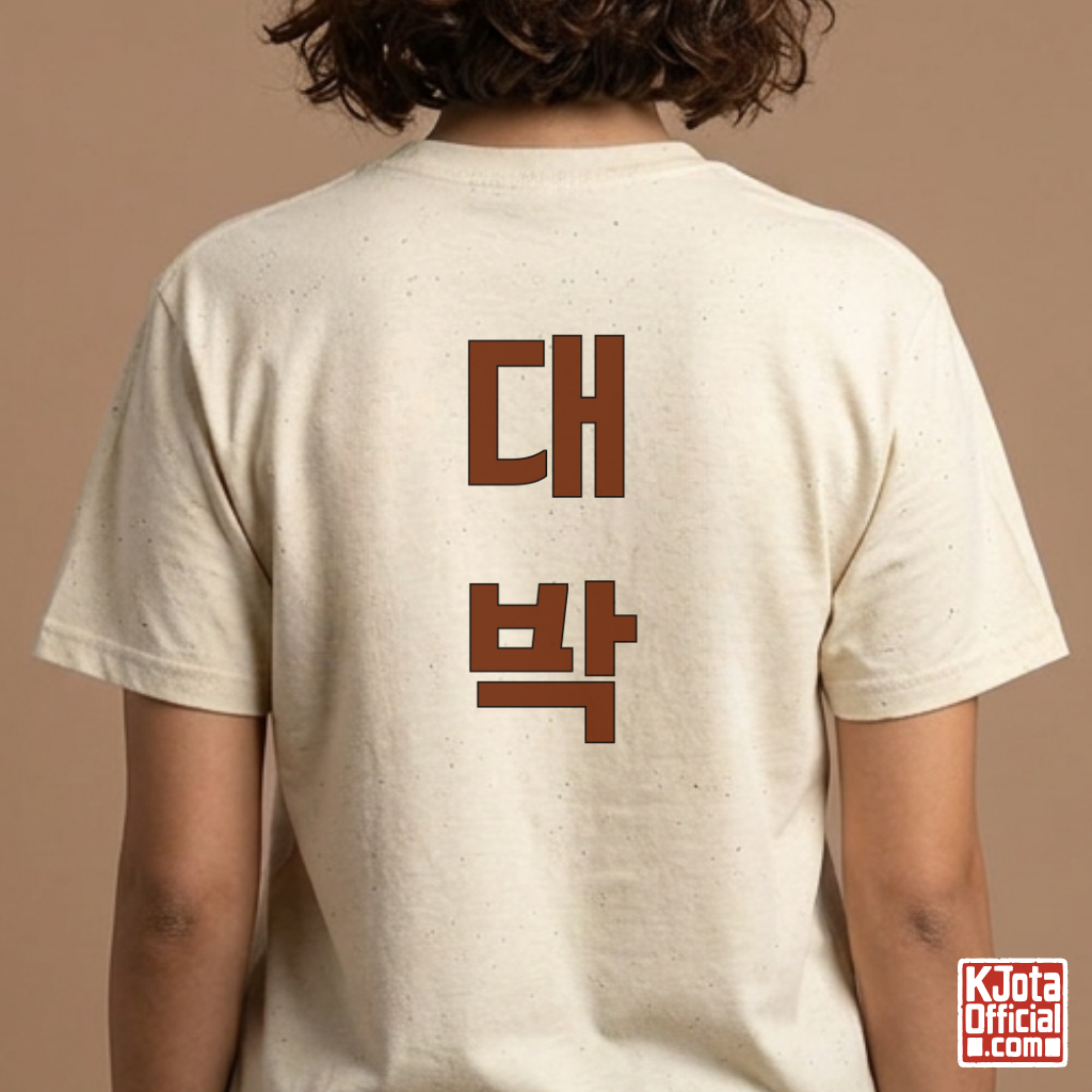 woman wearing a beige t-shirt with “대박” Daebak Korean text printed on back by K-Jota