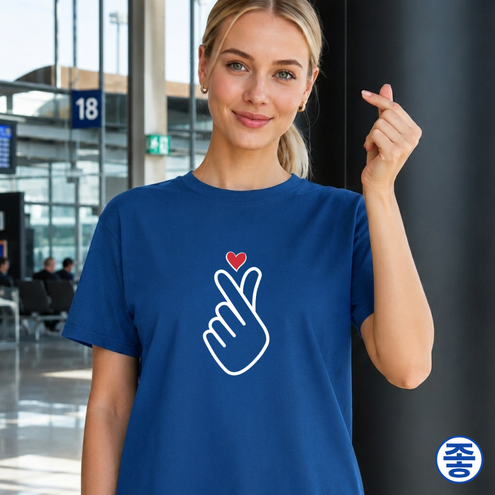 woman wearing finger heart Korean saranghaeyo K-pop Hallyu fan t-shirt blue by Kjota and making finger heart gesture at airport