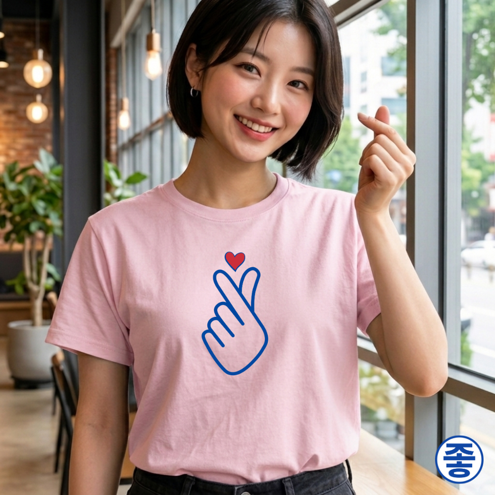 woman wearing finger heart Korean saranghaeyo K-pop Hallyu fan t-shirt pink by Kjota and making finger heart gesture at a modern cafe