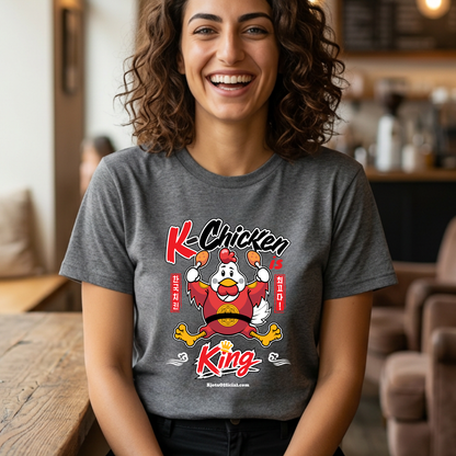 woman wearing “K-Chicken is King” graphic t-shirt in gray featuring a Korean fried chicken mascot wearing red royal robes holding fried chicken drumsticks with Hangeul text by Kjota
